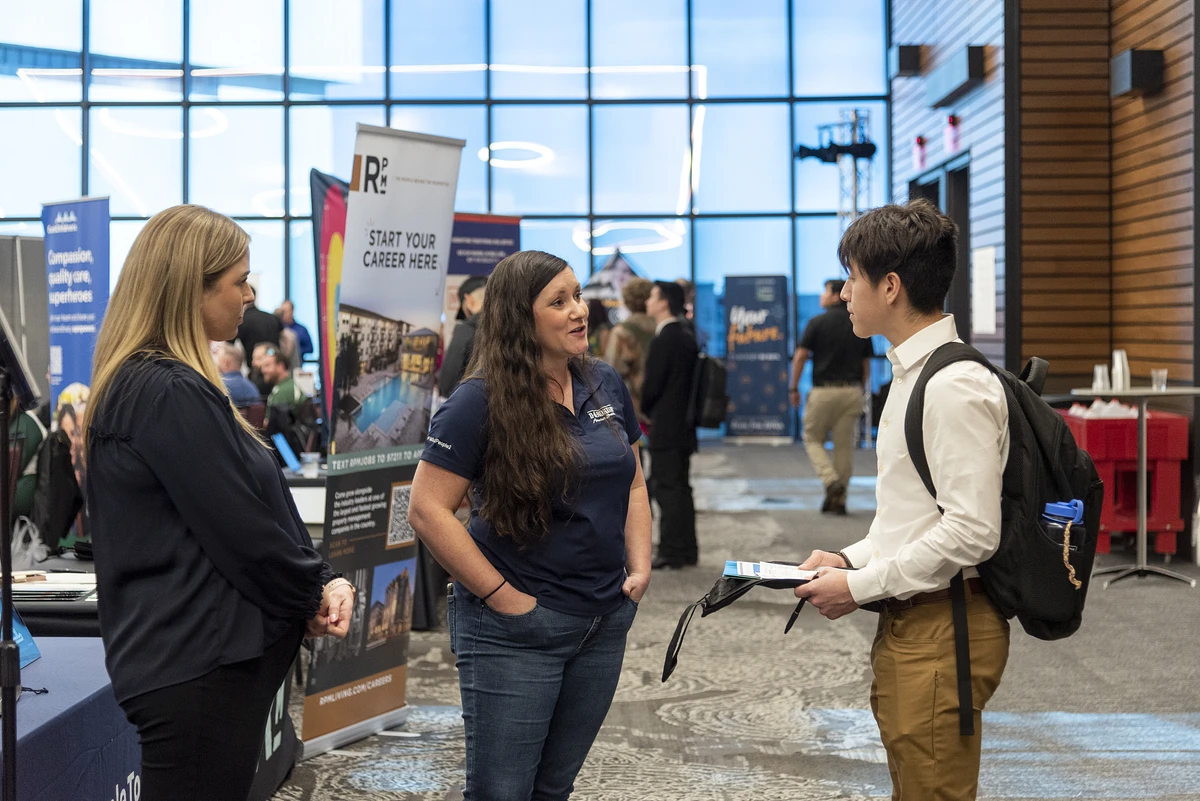 student speaking with employer representative at a career fair booth