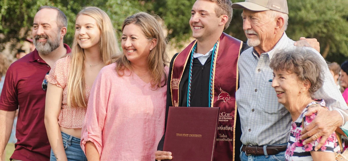 A family standing with a Texas State graduate