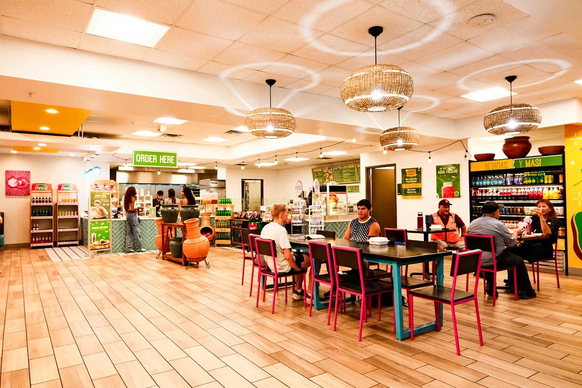 The image shows a casual eatery with people dining and ordering food at the counter.